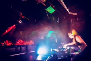 Young female DJ at record decks in nightclub, DJ Calixta